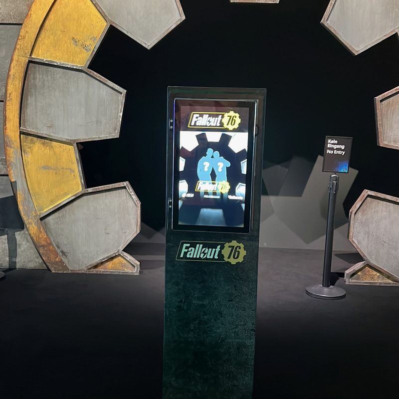 A themed, fully wrapped photobooth kiosk in front of a large set piece, its screen inviting guests to take their photo