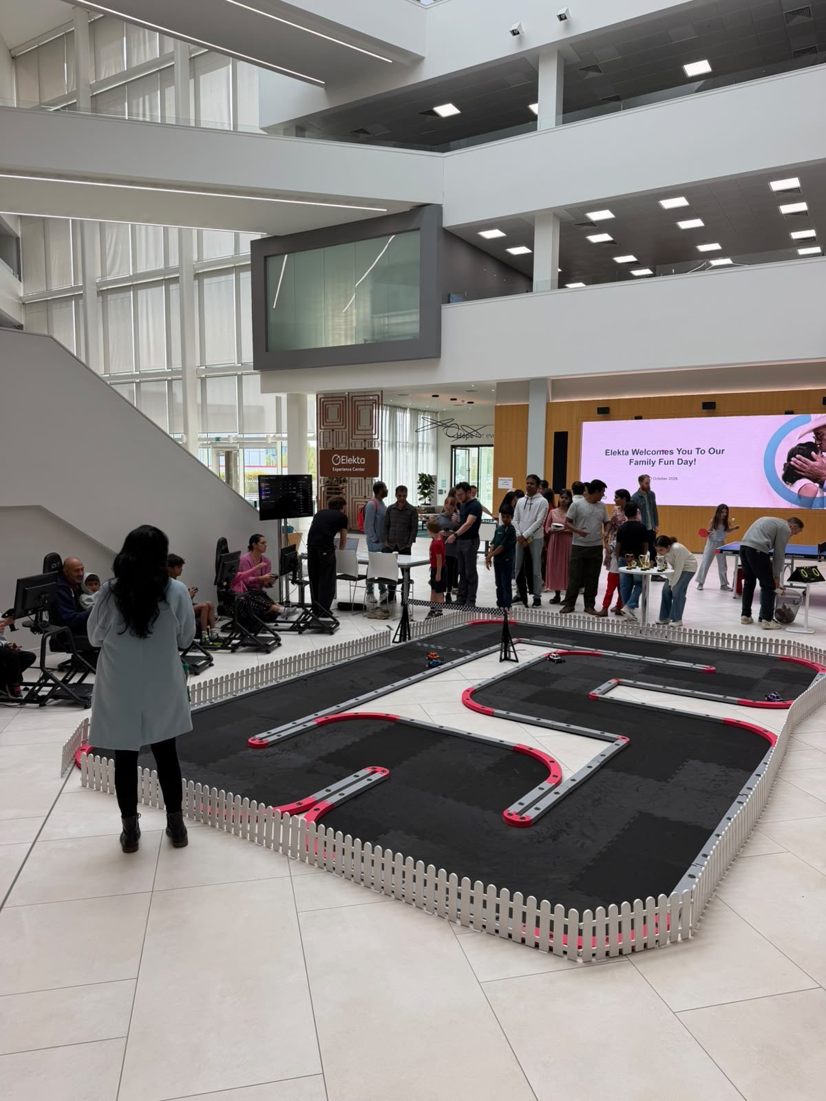 Guests gathered round the FPV RC racing track at Elekta's family fun day, with the welcome screen behind